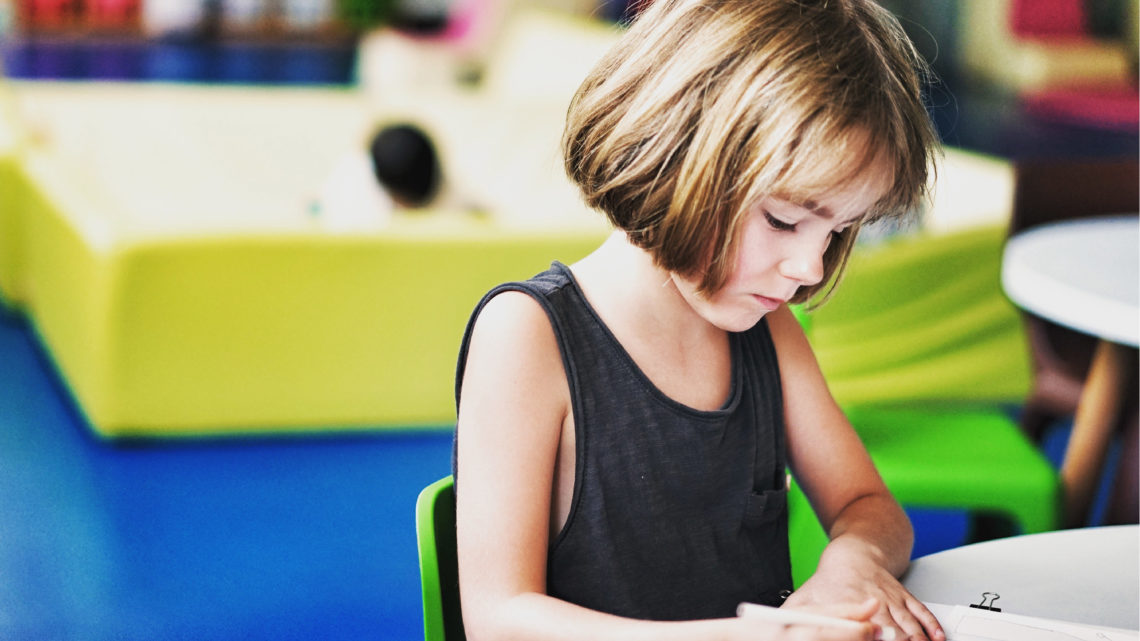 Elementary age girl writing at desk.